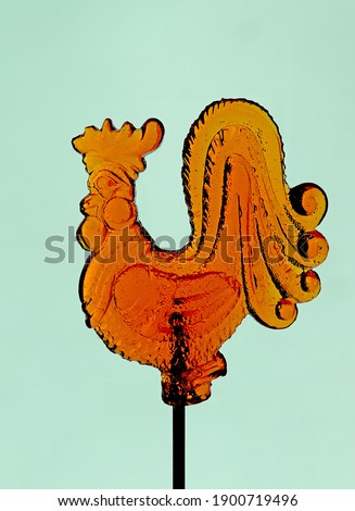orange rooster - candy lollipops on the mint background