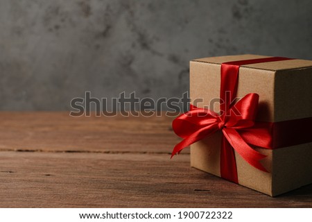 Selective focus of gift box with red ribbon and love shaped paper over rustic wooden table, top view flat lay.