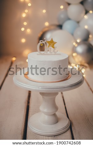 White cake in a stylish photo zone with a topper with the inscription one.