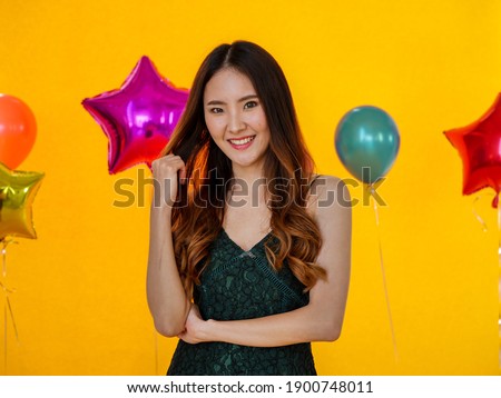 Portrait image of Asian lovely young woman standing on yellow background. Happy party lifestyle concept. 