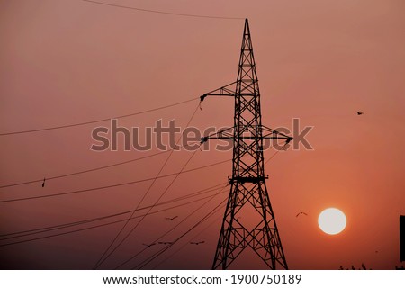 Beautiful picture of big electricity tower and big orange sun in background. Selective Focus On Subject