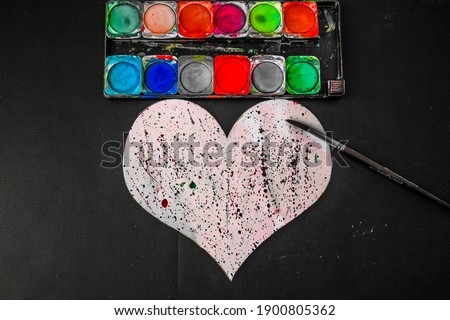 Watercolor work with spraying method on heart. Painting tools and materials.