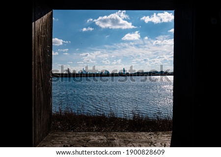 a landscape cityscape shot of the New York City skyline in the distance with the Freedom Tower as seen through a wooden window