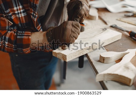 Craftsman cutting a wooden plank. Worker with wood. Man in a cell shirt.