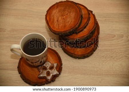 A cup and gingerbread are on stands with log cabins, saw cuts, slabs from a tree for decor