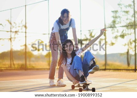 Asian Girl Friends Playing With Skateboard. Laughing and fun.