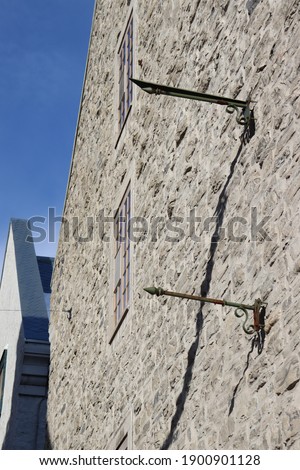 A stone wall with a window a metal pole and blue sky in old quebec
