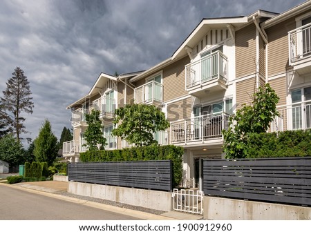 Residential condo building with fenced front yard on stormy sky background