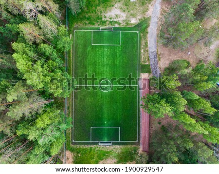 Aerial drone view of football soccer pitch field, green grass summer vibrant pitch playground in the forest, hidden in the woods