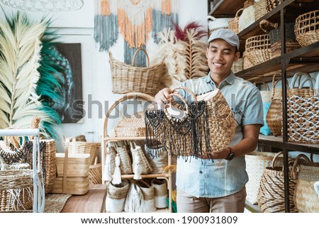 man in the hat holds and looks at the woven bag at the craft shop Royalty-Free Stock Photo #1900931809