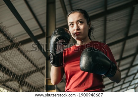 woman ultimate fighter in boxing gloves with movement hands defend beside copyspace on the ring arena