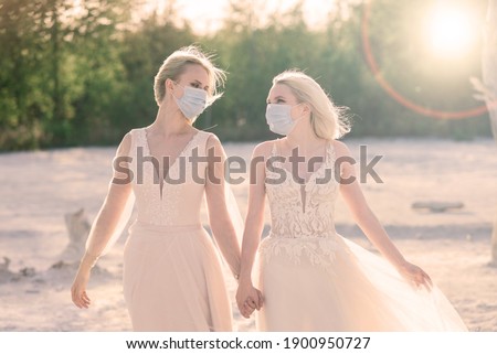 Lesbian couple wedding, wear masks to prevent epidemic covid, on sand background