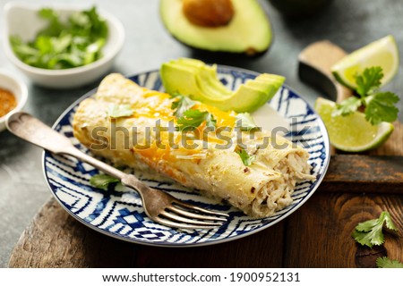 Green enchiladas on a plate topped with cheese and cilantro