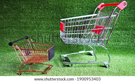Close up empty silver and brass shopping carts with green grass background. Shopping in supermarket idea.   Environmentally friendly concept.