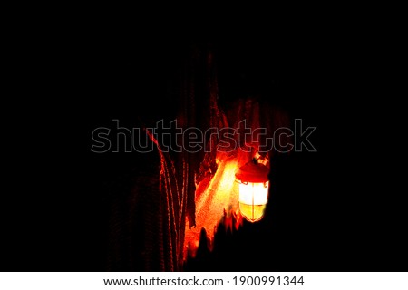 
The ghost holds a burning lantern on a dark background. Horror.