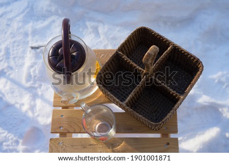 a glass teapot and a wicker basket stand on a wooden chair outside
