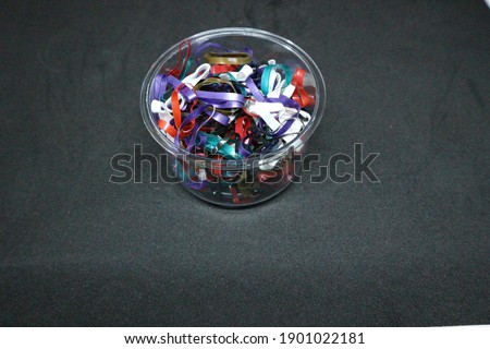 Hair colorful rubber bands in a clear plastic box placed on a black background.