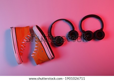 Sneakers and Two pairs of wireless stereo headphones in red blue neon light