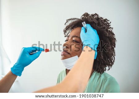 Coronavirus test - Medical worker taking a throat swab for coronavirus sample from a potentially infected woman with the isolation gown or protective suits and surgical face masks