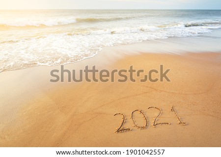 Numbers 2021 on the sandy beach at sunset, close-up. New year celebration concept. Idyllic panoramic seascape. Soft sunlight. Sand, sea water surface and waves texture. Graphic resources, copy space
