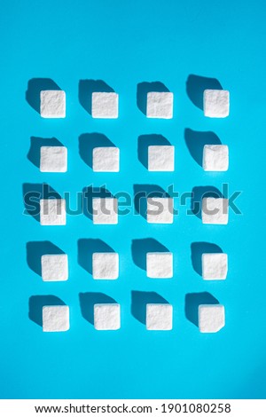 Tiny sugar cubes on a light blue background with sharp 3D shadows. Asymmetric pattern. Royalty-Free Stock Photo #1901080258