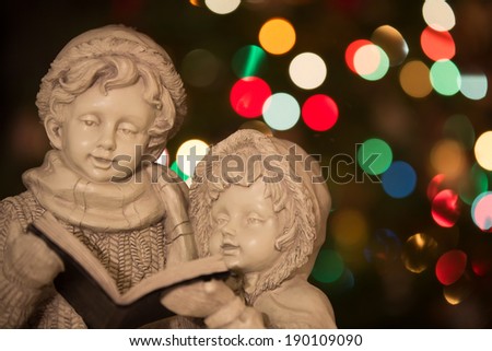 Christmas Carolers - statue of Christmas carolers / singers in front of Christmas tree with out of focus background.