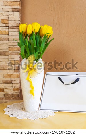 Yellow tulips in paper bag. Bright spring blooming flowers with copy space. Background for 8 March Mother Womens Day. Gift for woman. Flat lay. Beautiful bouquet of yellow tulips on a blue background