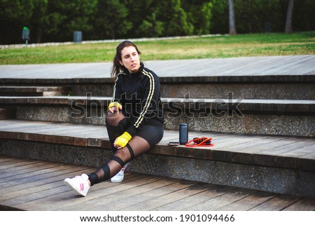 Portrait of a sporty young woman sit on wood stairs with sport accessories. 
