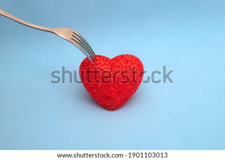 fork pricks a red heart on a blue background