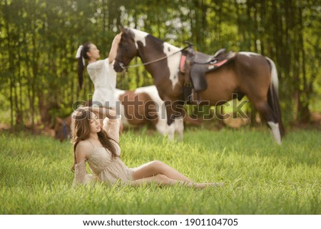 Beautiful asian woman spending a tranquil moment with a horse.Pretty Asian woman petting horse in a farm.