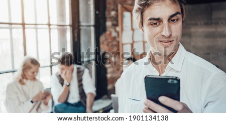 Office business team concept. Portrait of man using mobile phone and reading latest job news