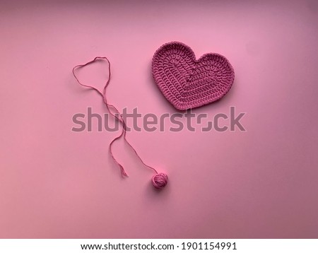 Knitted heart of pink color on a pink background.Photo from above. The concept of creating a product. Crocheting. The concept of Valentine's day
