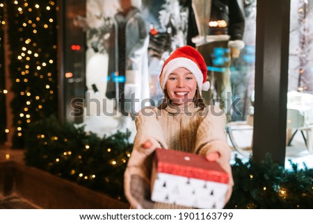 Young woman giving box for you outdoor. Gift exchange concept.