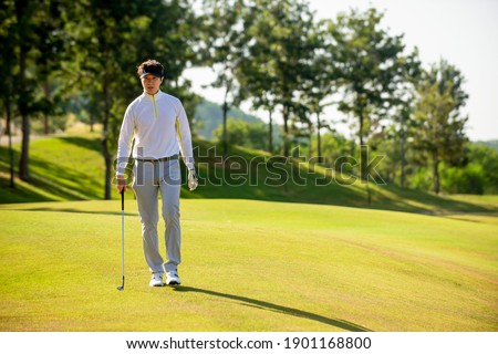 Asian man golfer  holding golf club walking  on fairway at golf course  , Sport healthy holiday lifestyle  Concept 