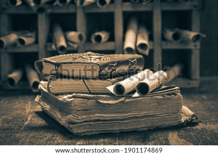 Old books and antique scrolls in library on wooden table Royalty-Free Stock Photo #1901174869