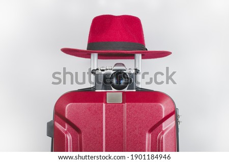 Red hat and camera Put it on the red suitcase Ready to travel for tourism White background