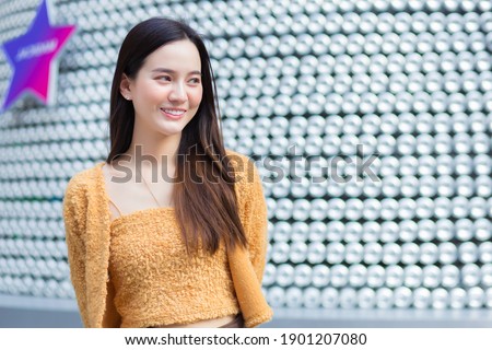 Asian pretty woman in long hair wears a yellow sweater and brightly smiles. abstract background.