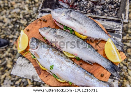 raw fish stuffed with lemon and herbs on the background of the sea