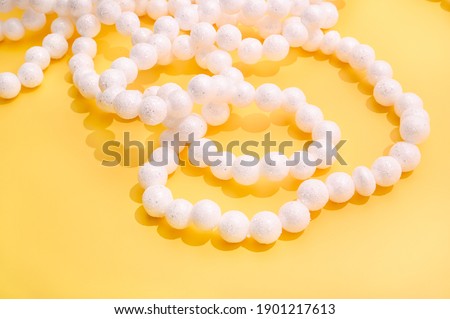 Elegant white garland on a bright yellow background. Creative holiday concept. Image for a poster or postcard on a festive theme. Copy space. High quality photo