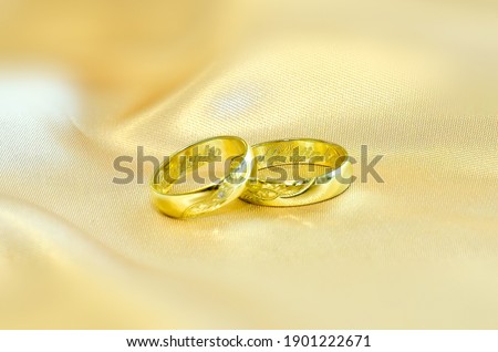 Two gold wedding rings on an elegant gold mat. Wedding rings with engraved names of the bride and groom. Rings for a wedding ceremony.