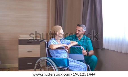 Doctor taking care of mature female patient sitting on wheelchair in hospital