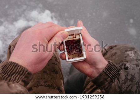 Man holding the box with fishing bait in his hand. Winter fishing on ice. Red bait. Putting bait on the hook. Winter fishing. High quality photo