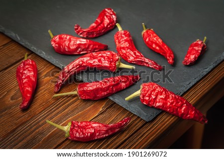Red pepper on a slate stone. A pile of dry red pepper lying on the wooden table. Hot chili peppers. Spices for cooking.