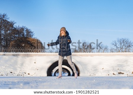 Young woman ice skating, winter sports, snow, winter fun. Woman learning to skate on the lake, nature, sunny day.