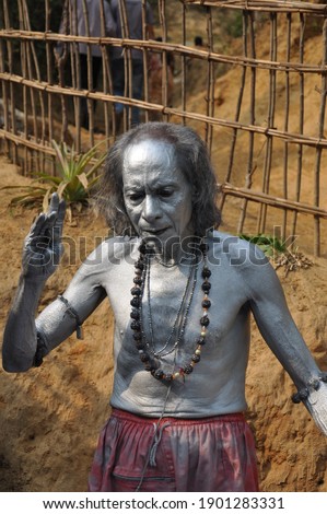 An Indian monk body painted with silver color, upholding his right  hand, Charak puja festival concept.