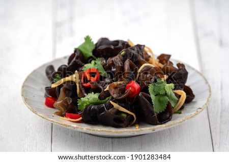 Boiled edible tree black fungus, wood ear in a plate on white table background. Royalty-Free Stock Photo #1901283484