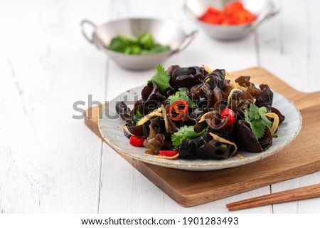 Boiled edible tree black fungus, wood ear in a plate on white table background. Royalty-Free Stock Photo #1901283493