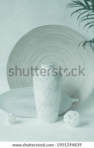 Interior vertical still life in pastel colors. Minimalist trendy style. Comfort and harmony in home design and decor. Decorative plates, balls, vase, palm plant in pot.