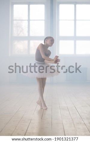 Cute little girl dreaming to become professional ballet dancer in a classical dance school