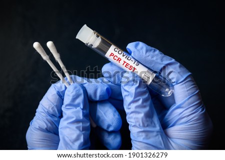 PCR test, COVID-19 swab collection kit in doctor's hands, nurse holds tube of corona virus PCR test on black background. Concept of nasal and oral PCR diagnostics, sample, health, result, treatment.